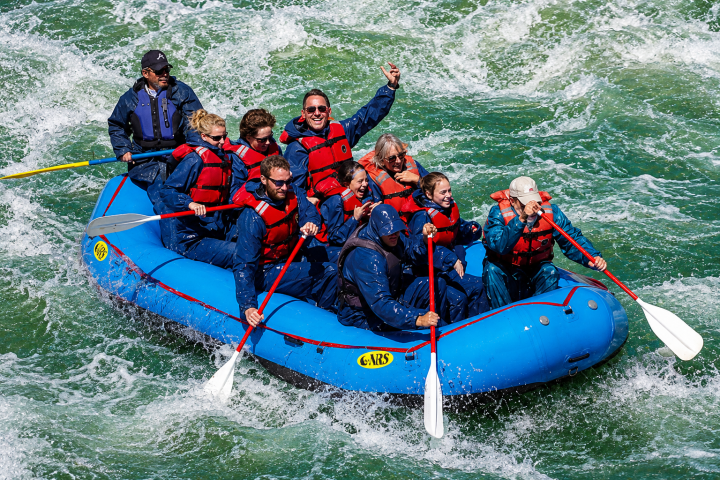 Group in blue raft navigating whitewater rapids.